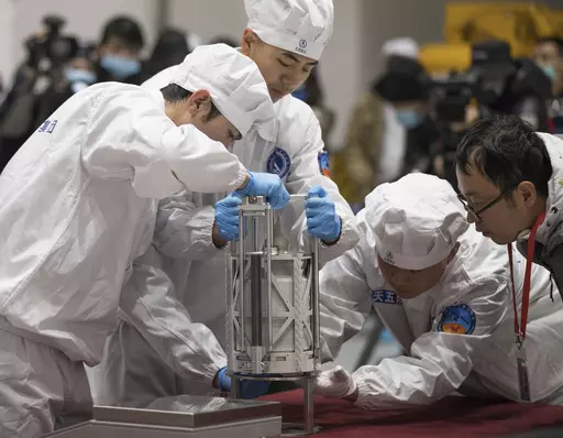 In this Thursday, Dec. 17, 2020 photo provided by China's Xinhua News Agency, technicians prepare to weigh a container carrying moon samples retrieved by China's Chang'e 5 lunar lander in Beijing. In a report published in the journal Nature Geoscience on Monday, March 27, 0223, scientists announced they have discovered a new and renewable source of water on the moon for future explorers in the lunar samples. Water was embedded in tiny glass beads in the lunar dirt where meteorite impacts occur. 