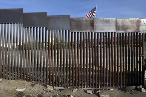 A United States flag flies behind the border fence that divides Mexico and the U.S., in Tijuana, Mexico, Nov. 21, 2018. Nearly a thousand migrants that recently crossed from Guatemala into Mexico formed a group Saturday, July 15, 2023, to head north together in hopes of reaching the border with the United States. (AP Photo/Rodrigo Abd, File)