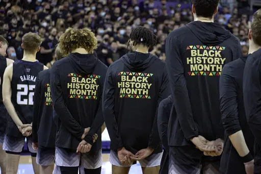 Washington players stand during the playing of the national anthem wearing warm-up jackets for Black History Month before an NCAA college basketball game against Arizona, Feb. 12, 2022, in Seattle. (AP Photo/John Froschauer, File)