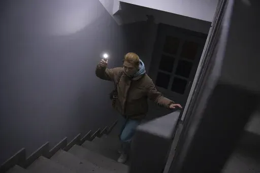 Anastasia Pyrozhenko, 25, climbs the stairs in her multi-storey apartment building in Kyiv, Ukraine, Sunday, Nov. 20, 2022. The lack of electricity turned Anastasia Pyrozhenko’s apartment into a deathtrap. Without electricity, there’s no water and no way to cook food, and the woman and her husband won’t even have time to run to the shelter from their 21st floor in the event of missile strikes, because the elevator isn’t working.  (AP Photo/Andrew Kravchenko)