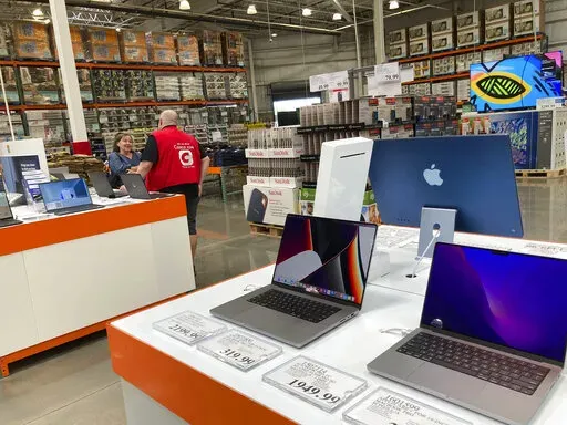 A sales associate helps a prospective customer as laptops sit on display in a Costco warehouse, Aug. 15, 2022, in Sheridn, Colo. Americans picked up their spending a bit in August from July even as surging inflation on household necessities like rent and food take a toll on household budgets. The U.S. retail sales rose an unexpected 0.3% last month, from being down 0.4% in July,  the Commerce Department said Thursday., Sept. 15, 2022. (AP Photo/David Zalubowski)