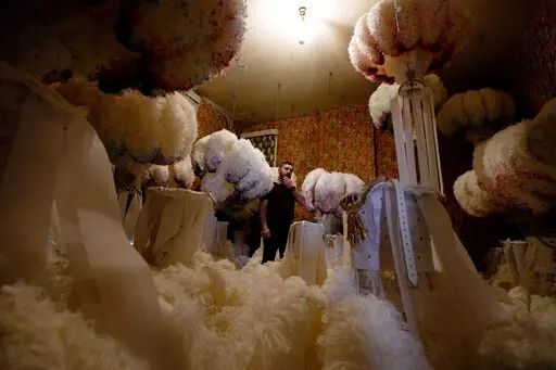 Quentin Kersten stands in the middle of a room full of ostrich feather hats in the Kersten family costume workshop in Binche, Belgium, Wednesday, Feb. 1, 2023. After a COVID-imposed hiatus, artisans are putting finishing touches on elaborate costumes and floats for the renowned Carnival in the Belgian town of Binche, a tradition that brings together young and old and is a welcome moment of celebration after a rough few years. (AP Photo/Virginia Mayo)