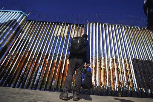 A migrant waits of the Mexican side of the border after United States Customs and Border Protection officers detained a couple of migrants crossing the US-Mexico border on the beach, in Tijuana, Mexico, Jan. 26, 2022. About 3 in 10 also worry that more immigration can cause native-born Americans to lose their economic, political and cultural influence, according to a poll by The Associated Press-NORC Center for Public Affairs Research. (AP Photo/Marco Ugarte, File)