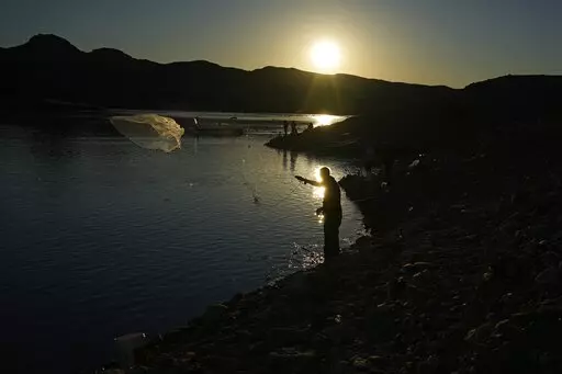 A fisherman throws a cast net along shore of Lake Mead at the Lake Mead National Recreation Area, Friday, Jan. 27, 2023, near Boulder City, Nev. Six western states that rely on water from the Colorado River have agreed on a plan to dramatically cut their use. California, the state with the largest allocation of water from the river, is the holdout. (AP Photo/John Locher)