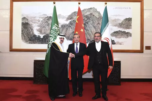 In this photo released by Xinhua News Agency, Ali Shamkhani, the secretary of Iran's Supreme National Security Council, at right, shakes hands with Saudi national security adviser Musaad bin Mohammed al-Aiban, at left, as Wang Yi, China's most senior diplomat, looks on, at center, for a photo during a closed meeting held in Beijing, Saturday, March 11, 2023. Iran and Saudi Arabia agreed Friday to reestablish diplomatic relations and reopen embassies after seven years of tensions. The major diplo
