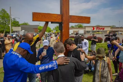 A group prays at the site of a memorial for the victims of the Buffalo supermarket shooting outside the Tops Friendly Market on Saturday, May 21, 2022, in Buffalo, N.Y. Funeral services are set for Friday for three of those killed: Geraldine Talley, Andre Mackniel and Margus Morrison. They are among the 10 people killed and three wounded May 14 when a white gunman opened fire on shoppers and employees at a Tops Friendly Market. (AP Photo/Joshua Bessex, File)