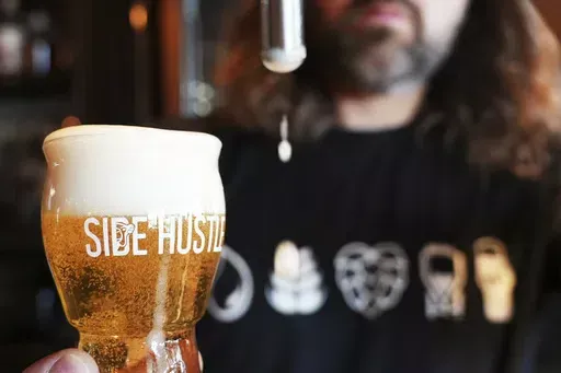 Mitchell Dougherty, the brewmaster at Side Hustle Brews and Spirts, pours a pint of beer at their brew pub in Abu Dhabi, United Arab Emirates, Monday, May 13, 2024. Abu Dhabi has overhauled its laws to allow for the micro and craft breweries that have taken the rest of the world by storm, part of a wider reconsideration of alcohol policies in this Islamic nation increasingly drawing tourists. (AP Photo/Malak Harb)