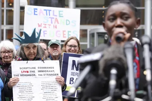 Retired reverend Carrol Jensen wears a hat mimicking the Statue of Liberty as Reverend Emilie Binja, a former refugee from the Democratic Republic of Congo speaks during a rally outside the U.S District Court after a federal judge blocked President Donald Trump's effort to halt the nation's refugee admissions system, Tuesday, Feb. 25, 2025 in Seattle. (AP Photo/Ryan Sun)