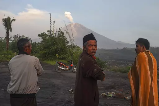 People watch as Mount Semeru spews volcanic materials from it crater in Lumajang, East Java, Indonesia, Monday, Dec. 5, 2022. Improved weather conditions Monday allowed rescuers to resume evacuation efforts and a search for possible victims after the highest volcano on Indonesia's most densely populated island erupted, triggered by monsoon rains. (AP Photo/Dicky Bisinglasi)