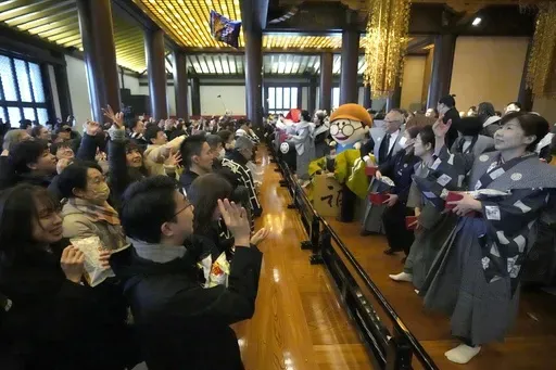 People try to catch lucky beans scattered by celebrities during the annual "Mame-maki," a ceremony marked in the hope of warding off evil spirits and inviting good luck, at the main hall of Zojoji Buddhist temple Tokyo Sunday, Feb. 2, 2025. (AP Photo/Eugene Hoshiko)