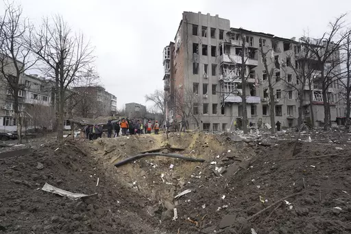 Municipal workers clear the rubble in front of a residential building damaged by a Russian missile strike in Kharkiv, Ukraine, Tuesday, Jan. 2, 2024. (AP Photo/Andrii Marienko)