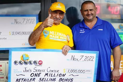 Business owner Joe Chahayed holds a check with his son, Joe Chahayed, Jr., as they pose for a picture outside his Joe's Service Center in Altadena, northeast of Los Angeles Tuesday, Nov. 8, 2022. CA Lottery officials presented a CA Lottery's retailer selling bonus check for "One Million US Dollars," for selling the lottery ticket that won a record $2.04 billion Powerball jackpot. (AP Photo/Damian Dovarganes)