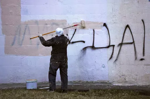 A worker paints over graffiti saying 'Yes to Peace!' on a wall of an apartment building in St. Petersburg, Russia, Friday, March 18, 2022. (AP Photo, File)