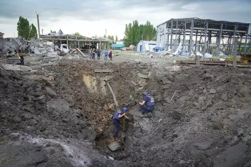 Police members inspect a crater caused by a Russian rocket attack in Pokrovsk, Donetsk region, Ukraine, Wednesday, June 15, 2022. (AP Photo/Efrem Lukatsky)