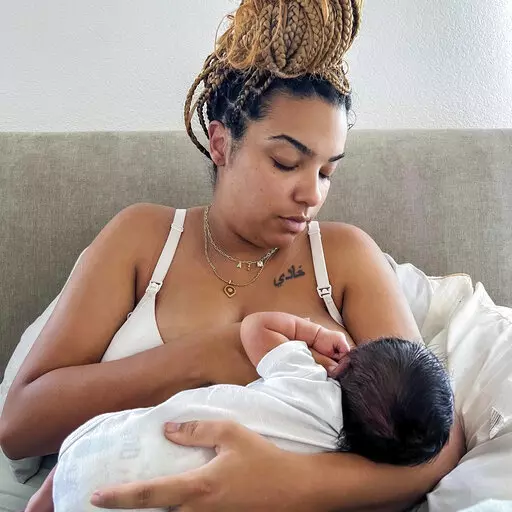 In this photo provided by Mark Godbolt Jr., his wife, Jade Godbolt, nurses her newborn child at their Dallas-area home in October 2022. She and her husband chose a home birth for their third child. Godbolt, 31, says there were no complications and she and her son are doing well. "I believed that my body could do what it was made to do and I wanted to be in the comfort of my home to do that,'' she said. (Mark Godbolt Jr. via AP)
