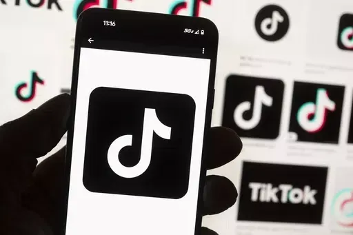 The TikTok logo is displayed on a mobile phone in front of a computer screen, Oct. 14, 2022, in Boston. TikTok is gearing up for a legal fight against a U.S. law that would force the social media platform to break ties with its China-based parent company or face a ban. A battle in the courts will almost certainly be backed by Chinese authorities as the bitter U.S.-China rivalry threatens the future of a wildly popular way for young Americans to connect online. (AP Photo/Michael Dwyer, File)