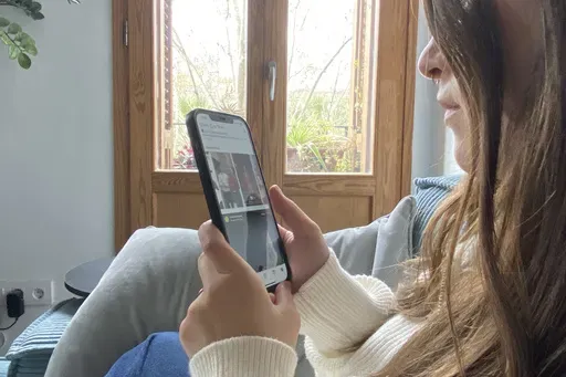 A woman checks social media on her phone in Barcelona Spain on March 25, 2025. (Albert Stumm via AP)