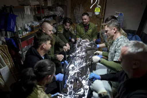 Ukrainian military medics of the 47th Brigade shift an injured comrade to a stretcher at the field hospital in Avdiivka direction, Donetsk region, Ukraine, Friday, May 10, 2024. (AP Photo/Evgeniy Maloletka)