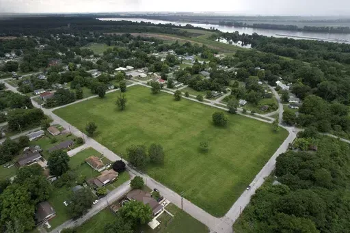 A vacant lot where, until recently, residences stood as a levee stands and Mississippi River flows past in the distance Thursday, May 23, 2024, in Cairo, Ill. Devastating flooding, driven in part by climate change, is taking an especially damaging toll on communities that once thrived along the banks of the river. (AP Photo/Jeff Roberson)