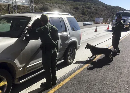 Border patrol agents use a drug sniffing dog to check vehicles at California's Pine Valley checkpoint, on the main route from Arizona to San Diego, Dec. 14, 2017 (AP Photo/Elliot Spagat, File)