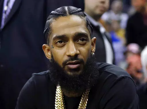Rapper Nipsey Hussle attends an NBA basketball game between the Golden State Warriors and the Milwaukee Bucks in Oakland, Calif., March 29, 2018. Eric R. Holder Jr., who was convicted last year of fatally shooting Hussle in 2019, is scheduled to be sentenced Wednesday, Feb. 22, 2023, in a Los Angeles courtroom. (AP Photo/Marcio Jose Sanchez, File)