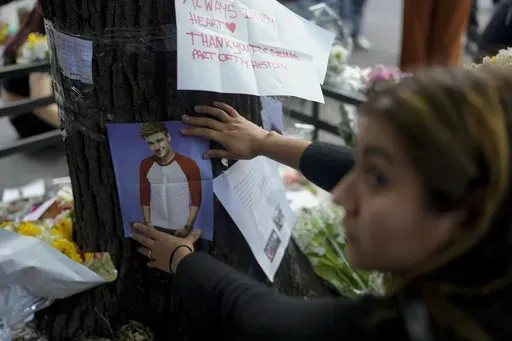A fan of former One Direction singer Liam places a photo of him on a tree outside the hotel where he was found dead after falling from a balcony the previous day in Buenos Aires, Argentina, Thursday, Oct. 17, 2024. (AP Photo/Natacha Pisarenko)