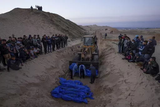 A bulldozer unloads the bodies of Palestinians killed in Israeli strikes and turned over by the Israeli military during a mass funeral in Rafah, Gaza Strip, Tuesday, Dec. 26, 2023. (AP Photo/Fatima Shbair, File)