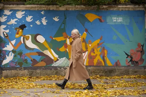 A woman walks by graffiti done in 2016 by Moldovan artists celebrating 25 years since the country declared its independence from the Soviet Union, in Chisinau, Moldova, Monday, Nov. 4, 2024. (AP Photo/Vadim Ghirda)