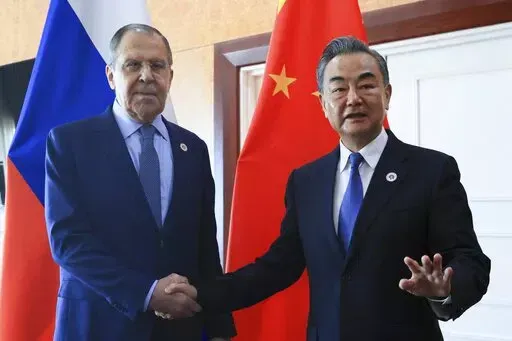 In this photo released by the Russian Foreign Ministry Press Service, Russian Foreign Minister Sergey Lavrov, left, and Chinese Foreign Minister Wang Yi pose for a photo prior to their talks on the sideline of the 12th East Asia Summit foreign ministers' meeting in Phnom Penh, Cambodia, on Aug. 5, 2022. Wang defended his country's position on the war in Ukraine on Sunday, Dec. 25, and signaled that China would deepen ties with Russia in the coming year while striving to bring US China ties back 