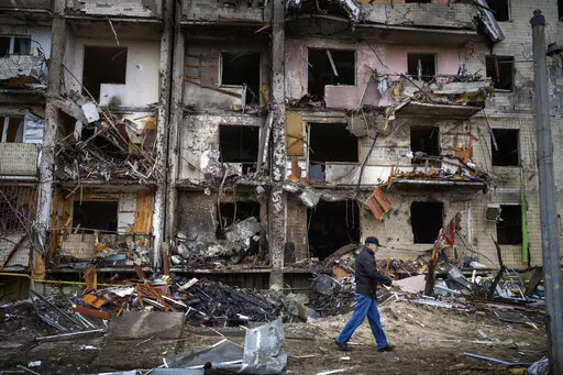 A man walks past a building damaged following a rocket attack, in Kyiv, Ukraine, Friday, Feb. 25, 2022.  The International Criminal Court's prosecutor has put combatants and their commanders on notice that he is monitoring Russia's invasion of Ukraine and has jurisdiction to prosecute war crimes and crimes against humanity. But, at the same time, Prosecutor Karim Khan acknowledges that he cannot investigate the crime of aggression. (AP Photo/Emilio Morenatti, File)
