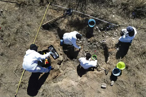 Forensic technicians excavate a field on a plot of land referred to as a cartel "extermination site" where burned human remains are buried, on the outskirts of Nuevo Laredo, Mexico, Tuesday, Feb. 8, 2022. The  insufficiency of investigations into Mexico’s nearly 100,000 disappearances is evident. There are 52,000 unidentified people in morgues and cemeteries, not counting places like this one, where the charred remains are measured only by weight. (AP Photo/Marco Ugarte)