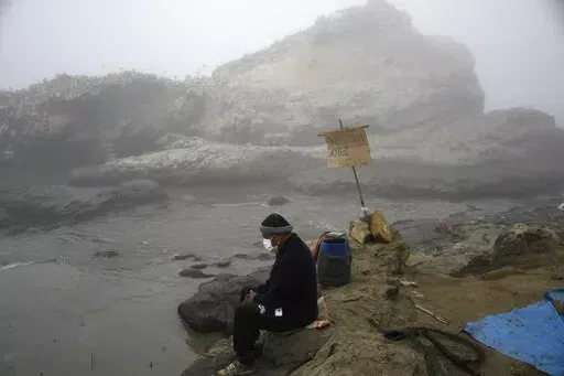 Fisherman Walter de la Cruz sits on the shore of the oil-stained Cavero Beach, unable to fish after a spill in the Ventanilla district of Callao, Peru, Jan. 21, 2022. De la Cruz, 60, is one of more than 2,500 fishermen whose livelihoods have been cast into doubt as a result of a large crude-oil spill by the Spanish-owned Repsol oil refinery on Jan. 15. (AP Photo/Martin Mejia, File)