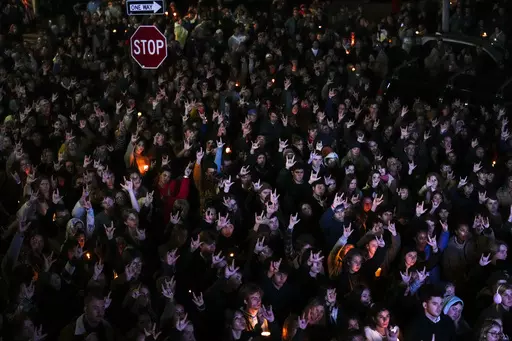 People sign "I love you," while gathered at a vigil for the victims of mass shootings days earlier, Sunday, Oct. 29, 2023, outside the Basilica of Saints Peter and Paul in Lewiston, Maine. Two senators from Maine are asking the U.S. Army inspector general to provide a full accounting of interactions with a reservist before he killed multiple people at a bowling alley and bar. (AP Photo/Matt Rourke, File)