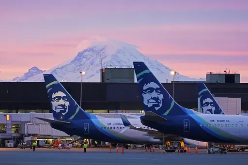 Alaska Airlines planes are shown parked at gates with Mount Rainier in the background at sunrise, March 1, 2021, at Seattle-Tacoma International Airport in Seattle. (AP Photo/Ted S. Warren, File)