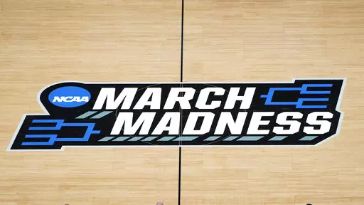 FILE -The March Madness logo is shown on the court during the first half of a men's college basketball game in the first round of the NCAA tournament at Bankers Life Fieldhouse in Indianapolis, Saturday, March 20, 2021. Kansas, Villanova, North Carolina and Duke will play in the first Final Four to take place under the new world of “name, image and likeness” endorsements in college sports. It allows college players to earn money through endorsements. (AP Photo/Paul Sancya, File)