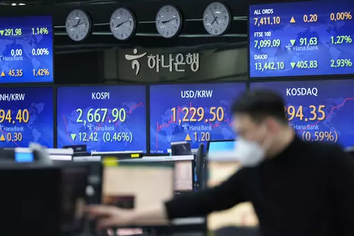 A currency trader watches computer monitors near the screens showing the Korea Composite Stock Price Index (KOSPI), center left, and the foreign exchange rate between U.S. dollar and South Korean won, center right, at a foreign exchange dealing room in Seoul, South Korea, Friday, March 11, 2022. Shares fell Friday in Asia as uncertainty over the war in Ukraine and persistently high inflation keep their sway over markets. (AP Photo/Lee Jin-man)
