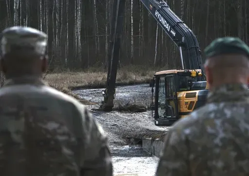 In this image provided by the U.S. Army, U.S. Army soldiers from the 1st Armored Brigade Combat Team, 3rd Infantry Division, along with Lithuanian Army and emergency services personnel, discuss their plan to recover four U.S. soldiers in a U.S. Army M88 Hercules submerged under several meters of water in a swamp near a training area near Pabadre, Lithuania, Thursday, March 27, 2025. (Christopher Saundersn/U.S. Army via AP)