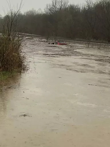 In this photo provided by Layton Hoyer, a red SUV is seen submerged in floodwater on Old Ritchey Road in Granby, Mo., early Friday, March 24, 2023. Hoyer rescued an elderly woman from the car. (Layton Hoyer via AP)