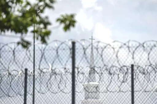 A church steeple peaks over the barbed-wire fence following the dedication of the newly constructed chapel at the Mississippi Correctional Institute for Women (MCIW) at Central Mississippi Correctional Facility in Pearl, Miss., June 15, 2023. A former Mississippi prison guard on Thursday, July 27, pleaded guilty to deprivation of an inmate's rights by using excessive force when she was a corrections officer at the Central Mississippi Correctional Facility, the U.S. Justice Department said. (Hann