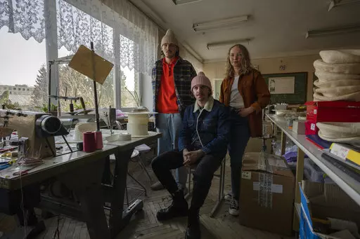 Ukrainian co-founders of high-end hat designer brand Ruslan Baginskiy 'RB', from left, public relations director Petro Yasinskiy, designer and creative director Ruslan Baginskiy and Victoria Semerei, whole sale director, pose for a photograph, inside a college classroom turned into a workshop they have been working from after fleeing Kiev, in Lviv, western Ukraine, Friday, March 25, 2022. Daily bombings led the company's co-founders to make the decision to flee. (AP Photo/Nariman El-Mofty)