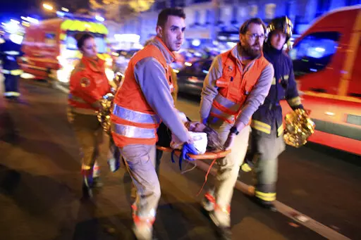 In this Nov. 13, 2015, file photo, a woman is evacuated from the Bataclan concert hall after a shooting in Paris. The last surviving suspect from the 2015 Paris attacks has told a court he felt "ashamed" after failing to detonate his suicide vest on the bloody night of Nov. 13. (AP Photo/Thibault Camus, File)