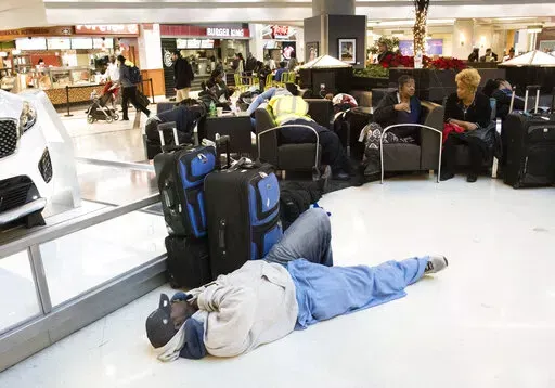 A man sleeps on the terminal floor at Hartfield-Jackson Atlanta International Airport on Dec. 18, 2017, in Atlanta. Transportation Secretary Pete Buttigieg has warned airlines that his department could draft new rules around passenger rights if the carriers don’t give more help to travelers trapped by flight cancellations and delays. The Transportation Department on Friday, Aug. 19, 2022, released a copy of the letters, which it said were sent to CEOs of the major U.S. airlines, their regional