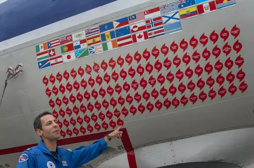 Lt. Commander Sam Urato, a P-3 pilot of National Oceanic and Atmospheric Administration, points to decals on the fuselage of the Lockheed WP-3D Orion 'hurricane hunter' aircraft representing the hurricanes it has penetrated during a hurricane awareness tour at Washington National Airport, Arlington, Va., Tuesday, May 3, 2022. Hurricane season starts Wednesday, June 1, 2022, and it's looking busy because every factor out there is pointing to another nasty year in the Atlantic. (AP Photo/Gemunu Am