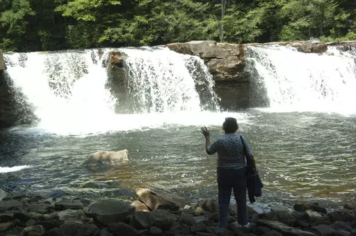 Eileen Lallone feels the mist from the waterfalls at the halfway point of the New Tygart Flyer scenic train ride on July 16, 2007, in Elkins, W.Va. A program offering cash and free outdoor adventures to remote workers to move to West Virginia with the hope of offsetting population losses has welcomed 143 new residents in the year since it launched, officials announced Tuesday, Nov. 29, 2022. (AP Photo/Dale Sparks, File)