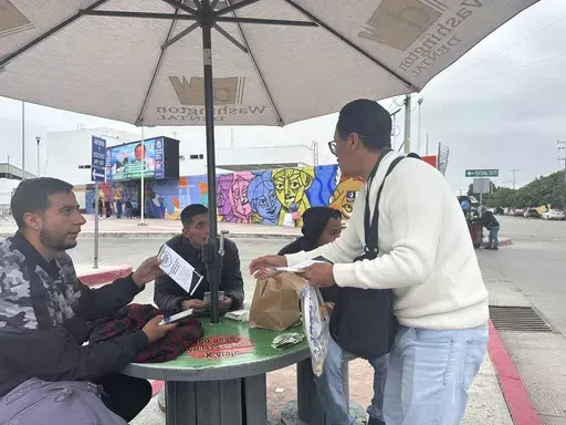Hugo López of Al Otro Lado advocacy group hands a pamphlet to Antonio Cortes, a Mexican man who was deported from the U.S. to Tijuana, Mexico, on June 11, 2024. Many migrant shelters across Mexico's border with the United States have seen little impact since President Joe Biden's suspended asylum last week, but they are preparing for more people. (AP Photo/Elliot Spagat)