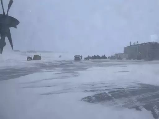 This March 28, 2023, photo shows townspeople in Gambell, Alaska, waiting in a snowstorm on four-wheelers to transport Alaska National Guard personnel from the air strip to the school for a ceremony. Sixteen Alaska National Guard members were honored for helping rescue the 11 crew members of a Navy plane that was shot down in 1955 by Soviet jet fighters and crash-landed about 8 miles from Gambell, on St. Lawrence Island, and 15 medals were presented posthumously. (AP Photo/Mark Thiessen)