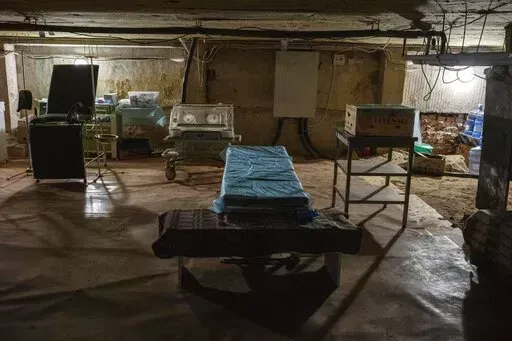 A makeshift operating area for urgent deliveries, inside the shelter of the Lviv state regional perinatal center, western Ukraine, Friday, April 1, 2022. In the dim basement, where heavily pregnant women must bend low to avoid the water pipes, there is a delivery table in case the baby comes amid the air raid sirens. (AP Photo/Nariman El-Mofty)