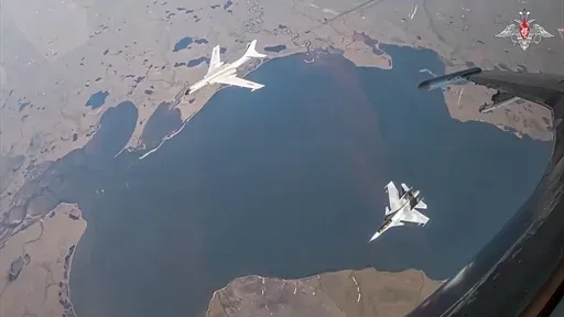 In this photo taken from video released by Russian Defense Ministry Press Service on Thursday, July 25, 2024, A H-6K long-range bomber of the Chinese air force, upper left, is seen escorted by a Su-30 fighter of the Russian air force during a joint Russia-China air patrol. (Russian Defense Ministry Press Service via AP)