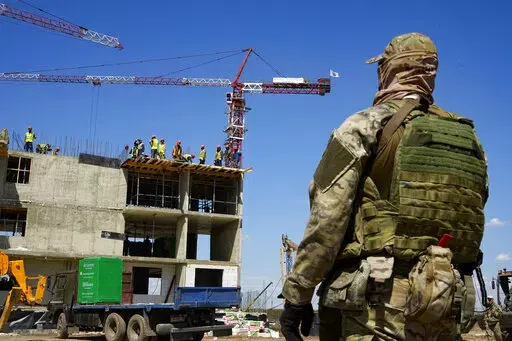 A Russian soldier guards the site of a new apartment building which is is being built with the support of the Russian Defense Ministry, in Mariupol, in territory under control of the government of the Donetsk People's Republic, in eastern Ukraine, Wednesday, July 13, 2022. This photo was taken during a trip organized by the Russian Ministry of Defense. (AP Photo/File)