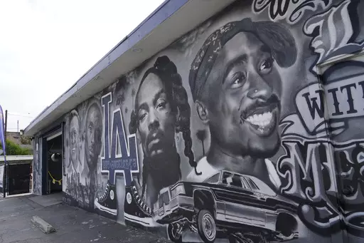 A portion of a mural by artist sloe_motions depicting Oscar De La Hoya, Vin Scully, Kobe Bryant, Snoop Dogg, and Tupac Shakur is seen on the side of Speedy Auto Tint on Friday, Sept. 29, 2023, in Bellflower, Calif. (AP Photo/Chris Pizzello)